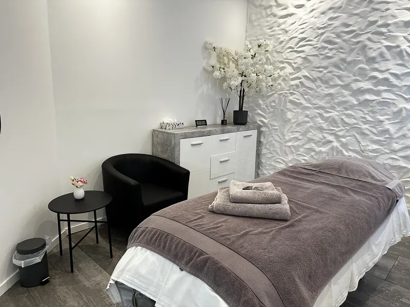 Gemütlicher Behandlungsraum mit Massageliege und weichen Handtüchern